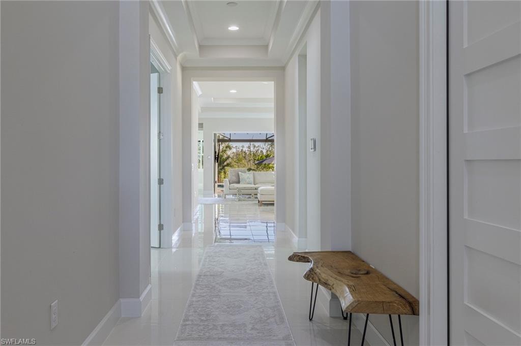 Corridor with light tile patterned flooring and a tray ceiling