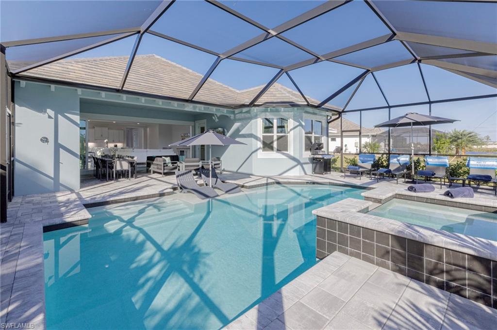 View of swimming pool featuring a lanai, a patio area, and an in ground hot tub