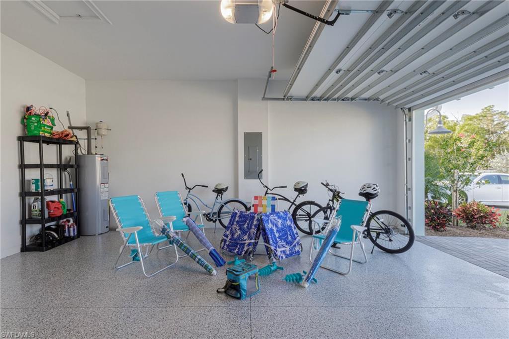 Garage featuring electric water heater, electric panel, and a garage door opener