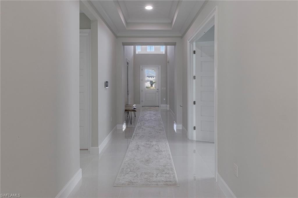Corridor featuring light tile patterned floors and a tray ceiling