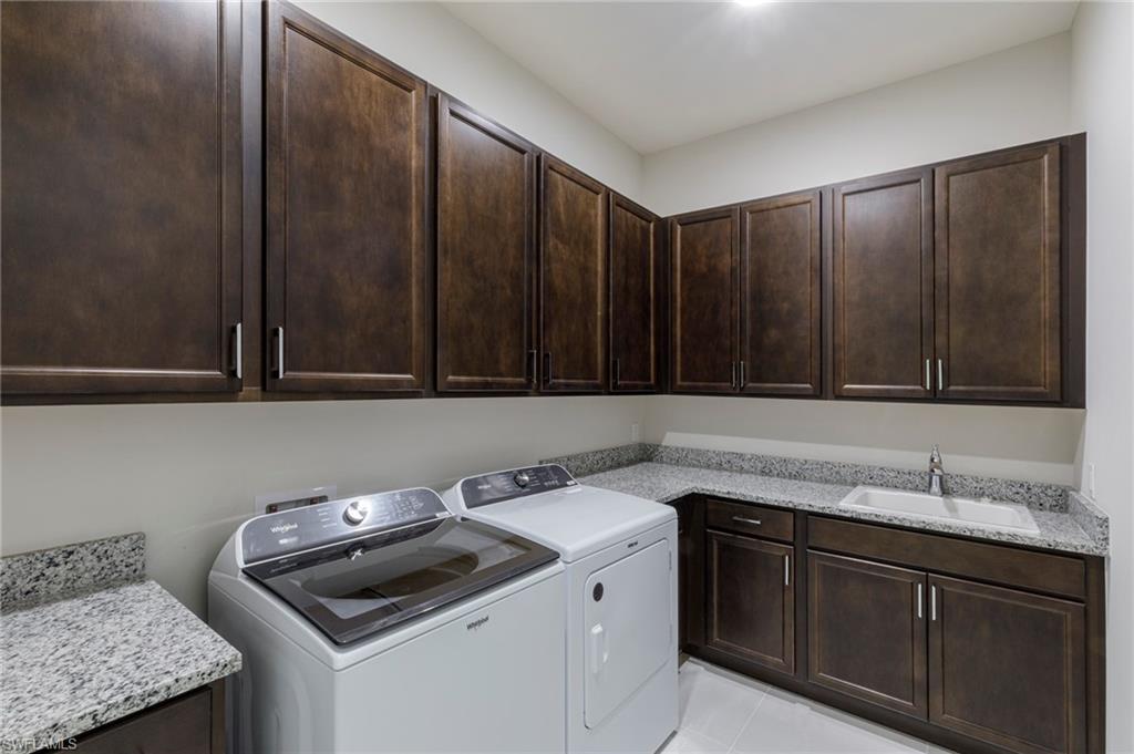 Laundry room with sink, light tile patterned floors, cabinets, and independent washer and dryer