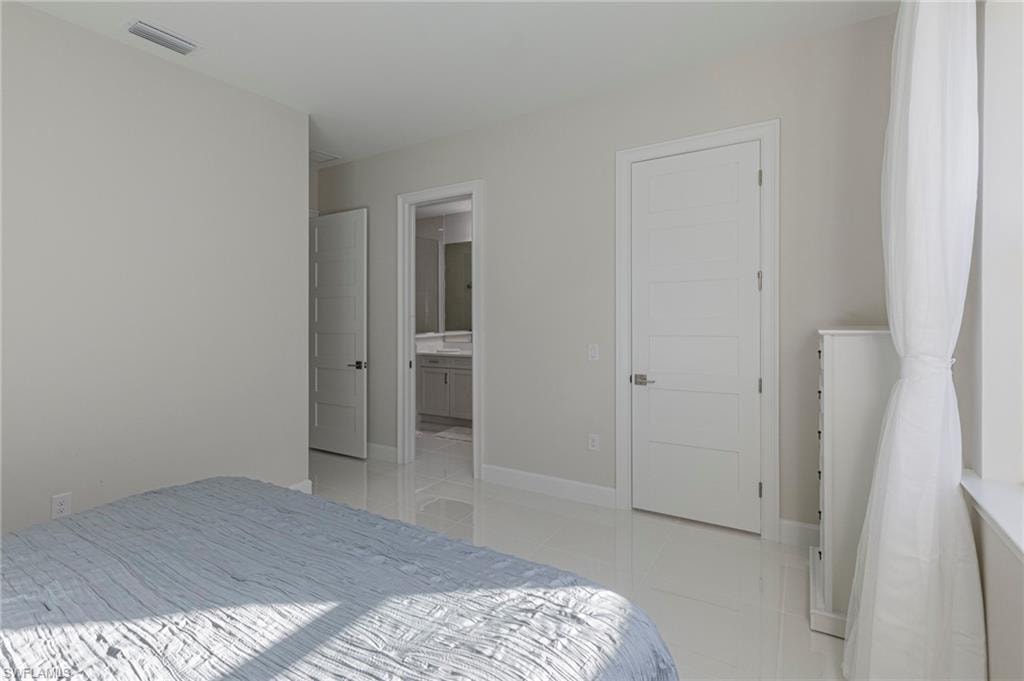 Bedroom featuring ensuite bathroom and light tile patterned floors