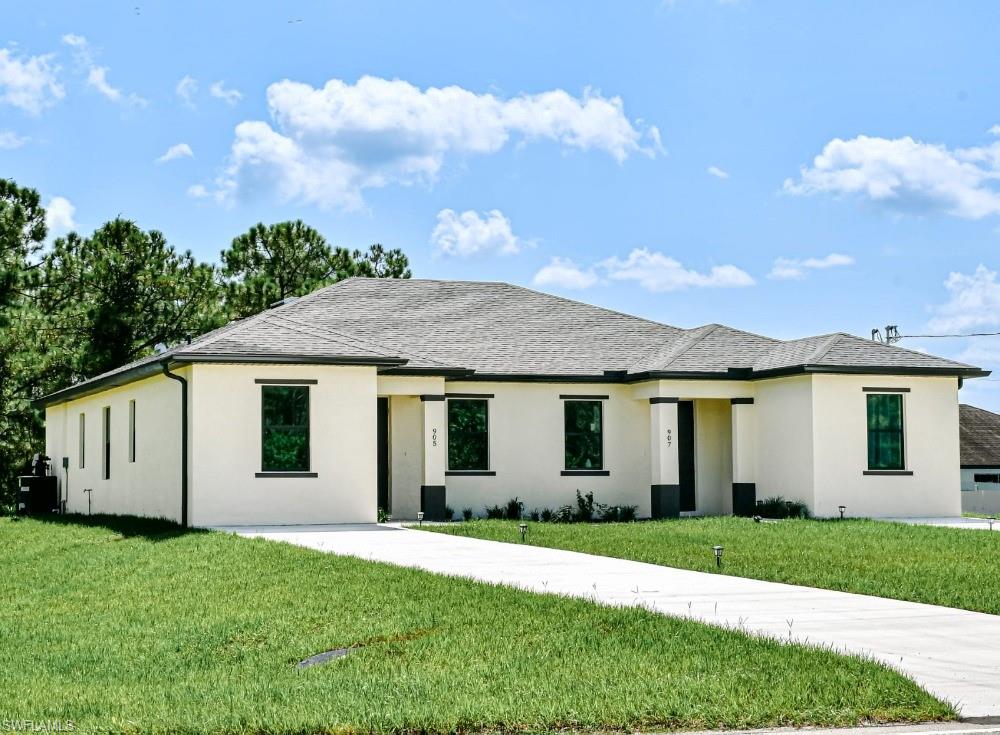 Prairie-style house featuring stucco siding, a front lawn, and a shingled roof
