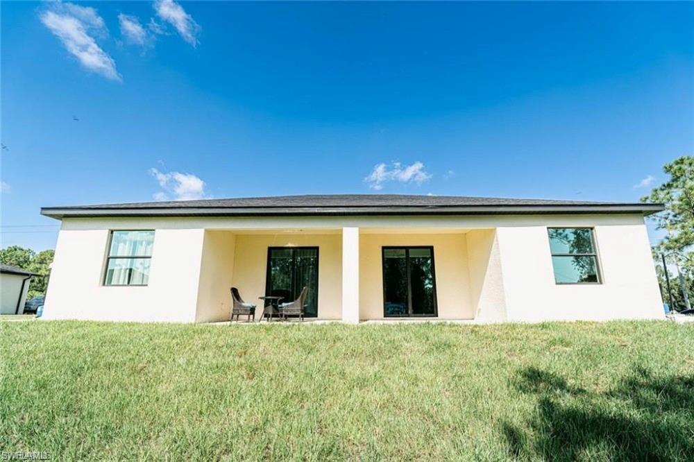 Rear view of property with stucco siding, a patio area, and a yard