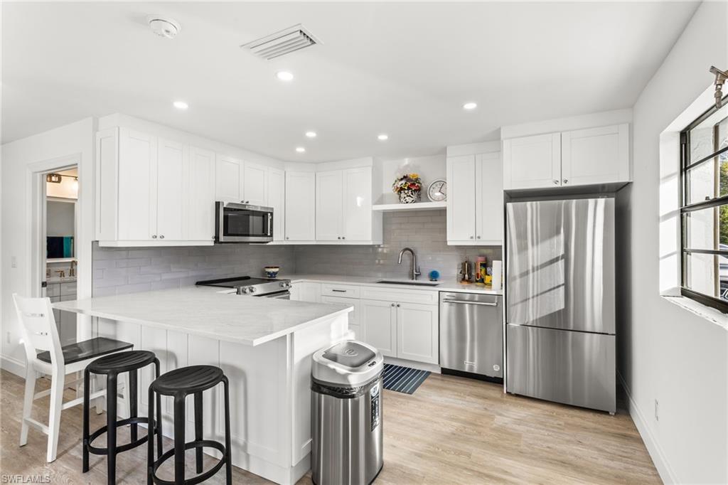 Kitchen featuring appliances with stainless steel finishes, white cabinetry, a peninsula, and recessed lighting