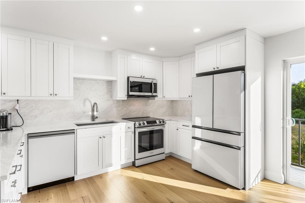 Kitchen with stainless steel appliances, white cabinetry, light stone countertops, tasteful backsplash, and recessed lighting