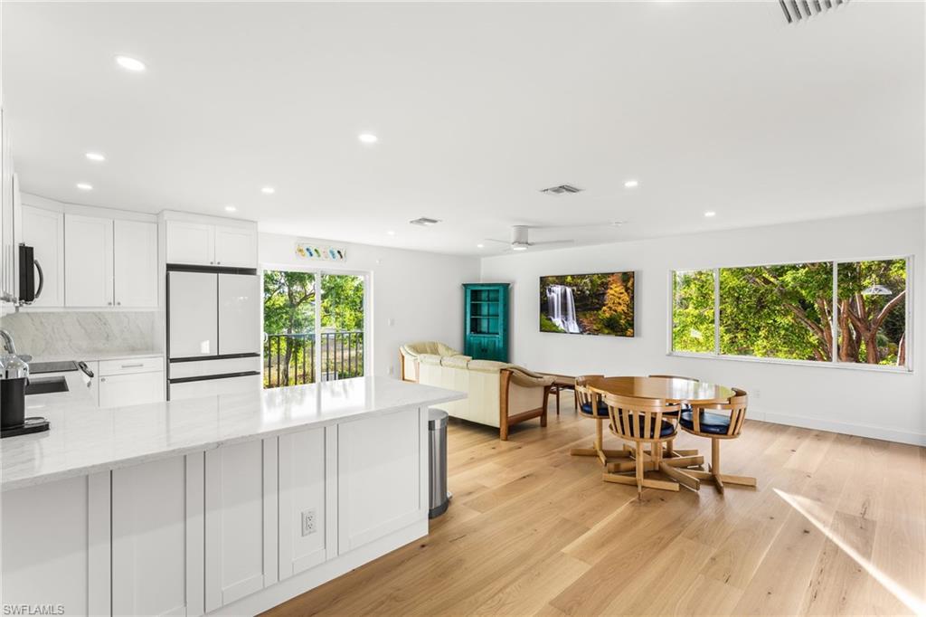 Kitchen with white cabinets, light stone counters, a peninsula, freestanding refrigerator, and recessed lighting