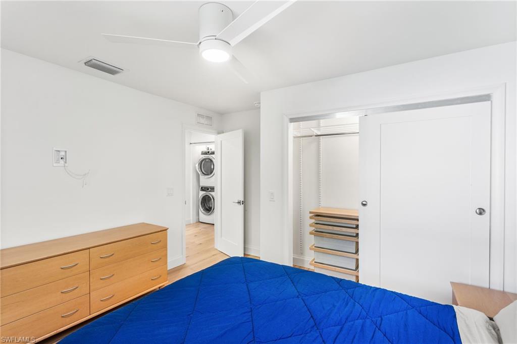 Bedroom featuring a closet, ceiling fan, stacked washer and clothes dryer, and light wood finished floors