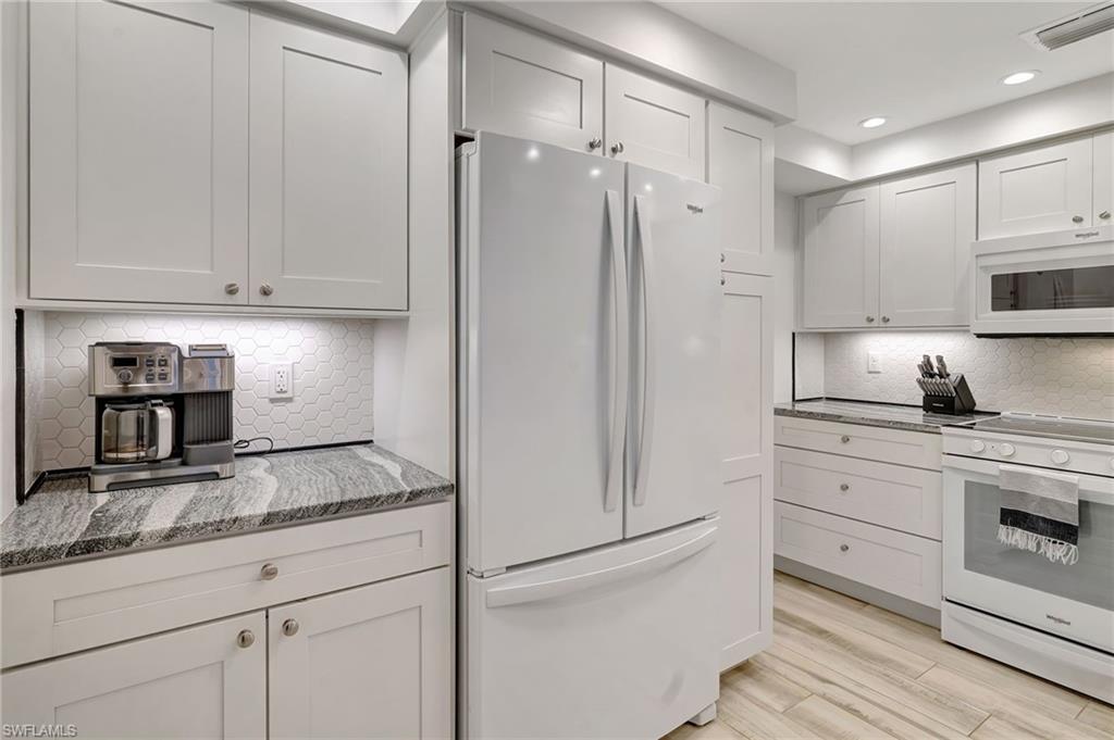 Kitchen featuring white appliances, tiled backsplash & recessed lighting