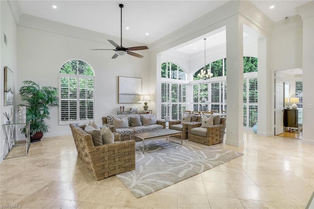 Living area with a chandelier, a high ceiling, crown molding, and ceiling fan