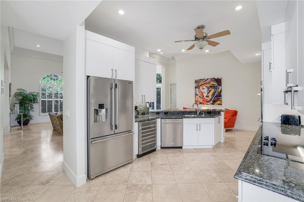 Kitchen featuring dark stone counters, plenty of natural light, appliances with stainless steel finishes, white cabinetry, and recessed lighting