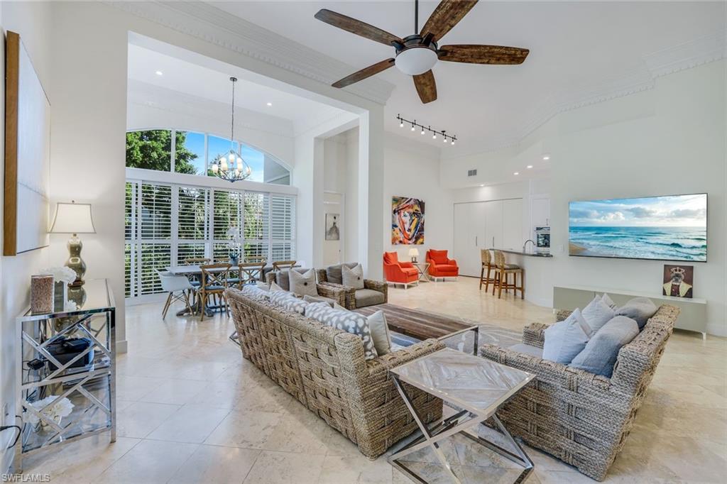 Living area with ornamental molding, ceiling fan, a chandelier, a high ceiling, and track lighting