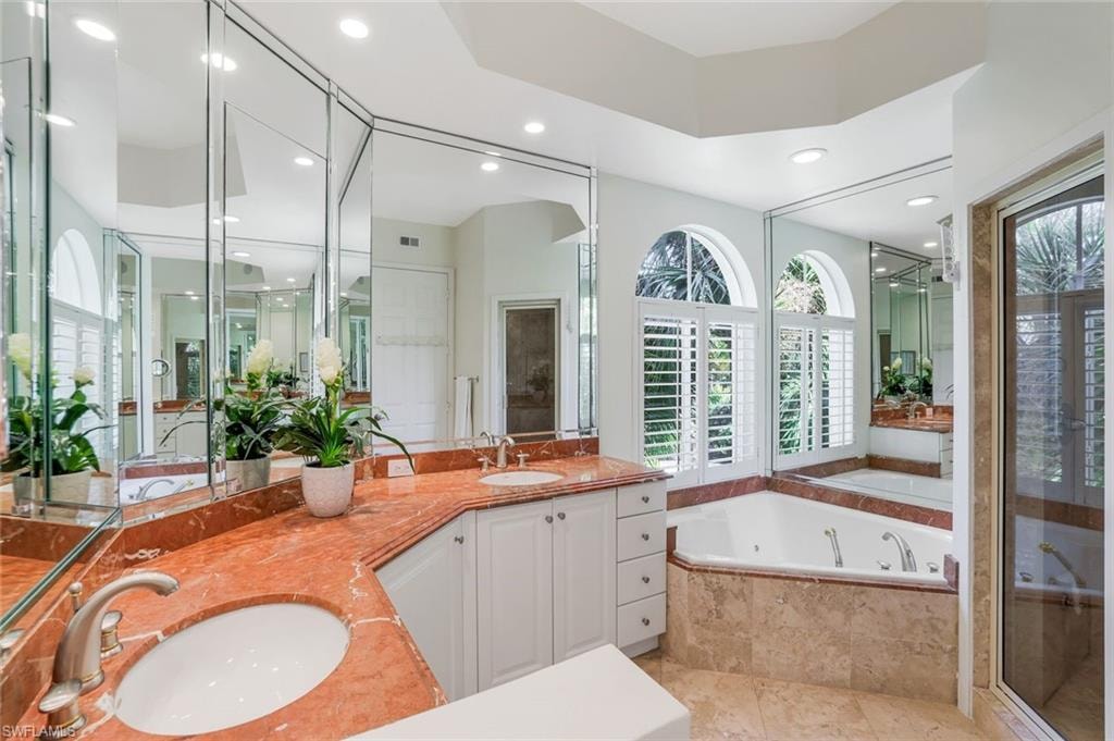 Full bathroom with double vanity, a garden tub, a shower stall, healthy amount of natural light, and recessed lighting
