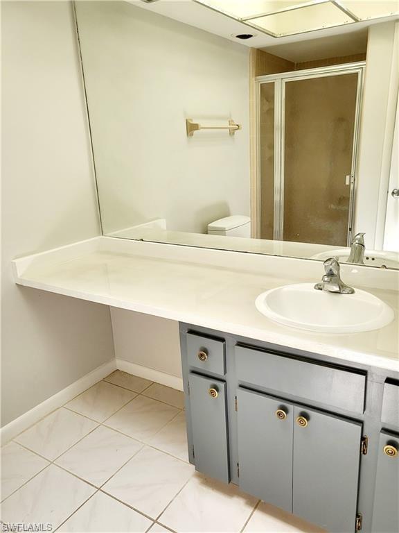 Full bath featuring vanity, light tile patterned flooring, and a stall shower