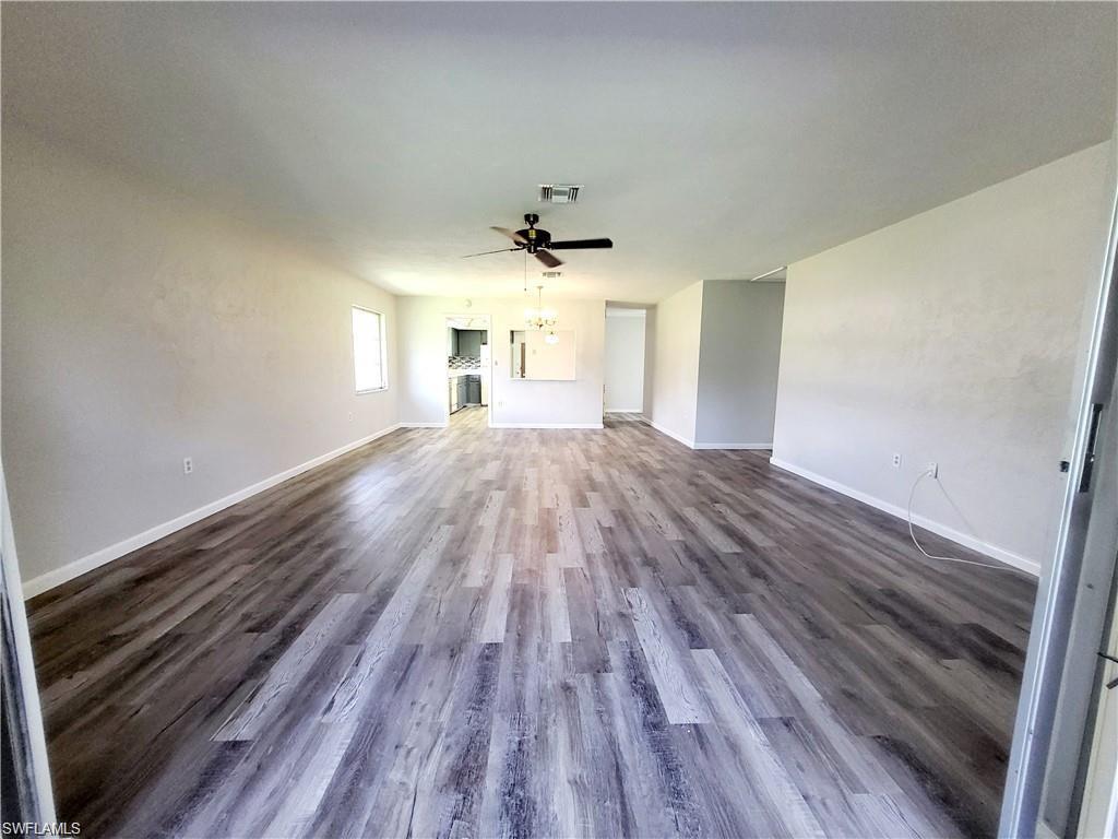 Unfurnished living room with dark wood-style floors and ceiling fan