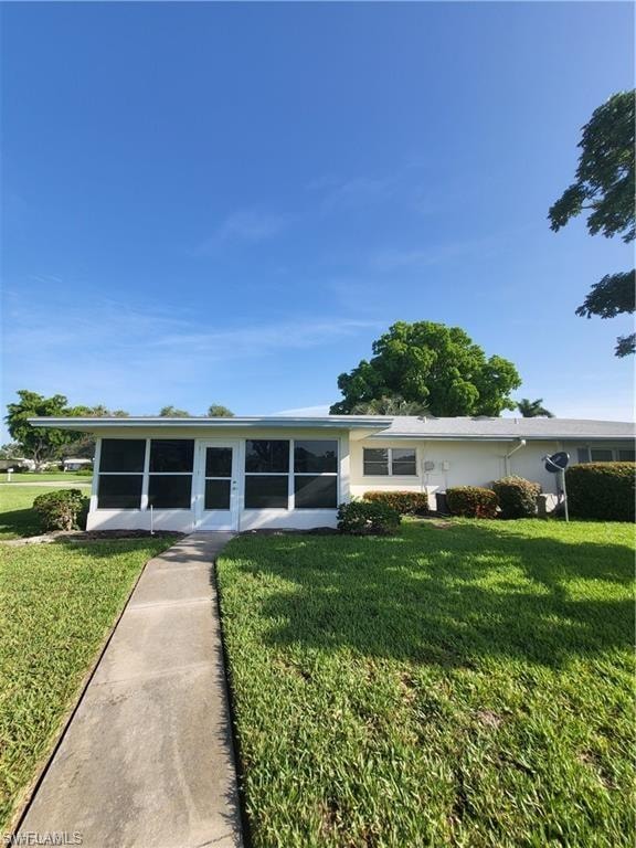 Back of house with a lawn and a sunroom