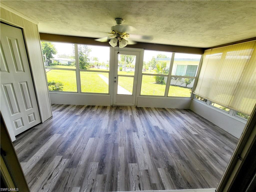 Unfurnished sunroom with wood finished floors and a textured ceiling