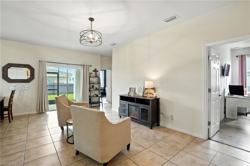 Living area featuring a desk, light tile patterned floors, a chandelier, and plenty of natural light