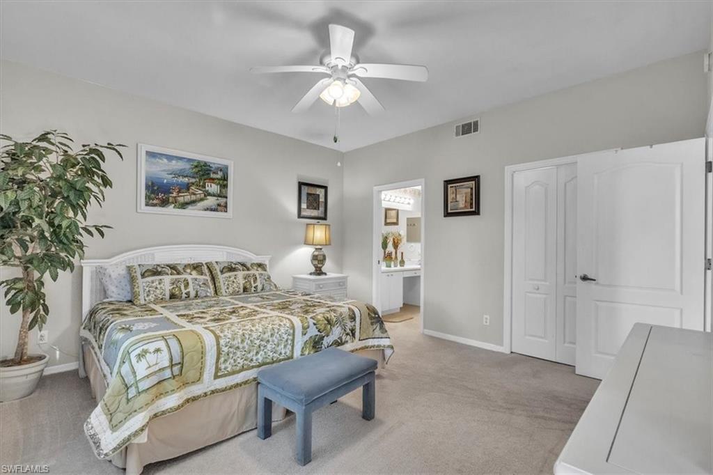 Bedroom featuring light carpet, a ceiling fan, and ensuite bath