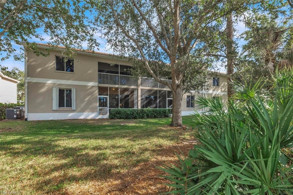 Back of property with a sunroom, stucco siding, a balcony, and a lawn