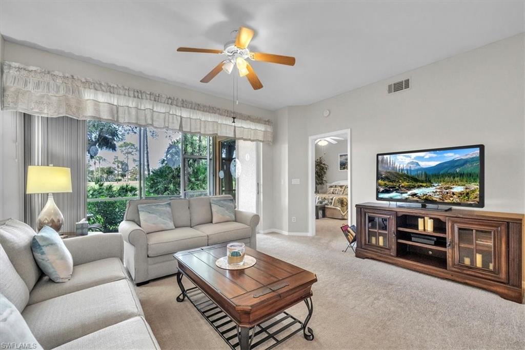 Carpeted living room featuring ceiling fan