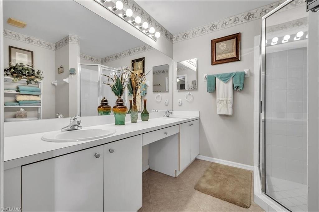 Bathroom with a stall shower, double vanity, and light tile patterned floors