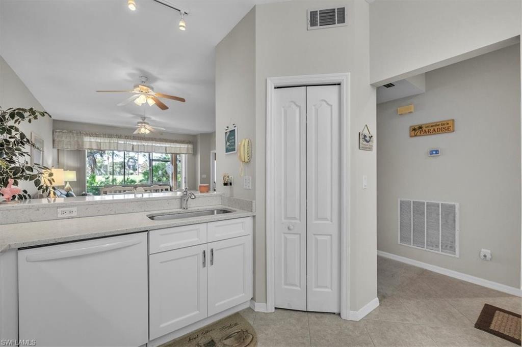 Kitchen featuring white dishwasher, ceiling fan, white cabinets, light tile patterned floors, and light stone counters