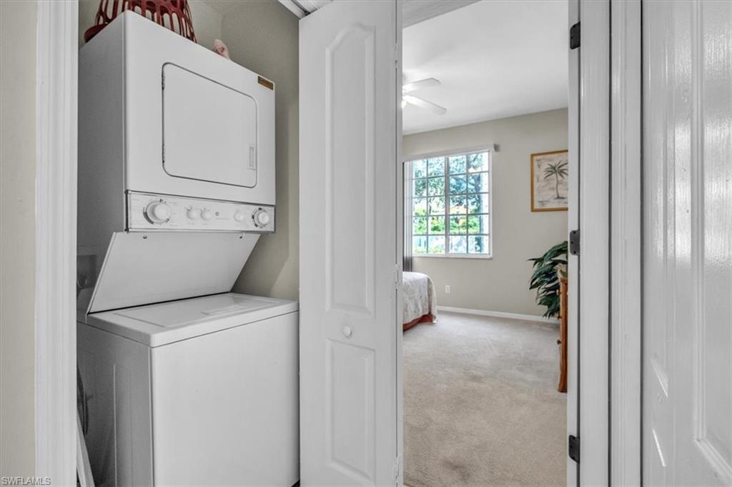 Washroom featuring light carpet, stacked washer and clothes dryer, and a ceiling fan