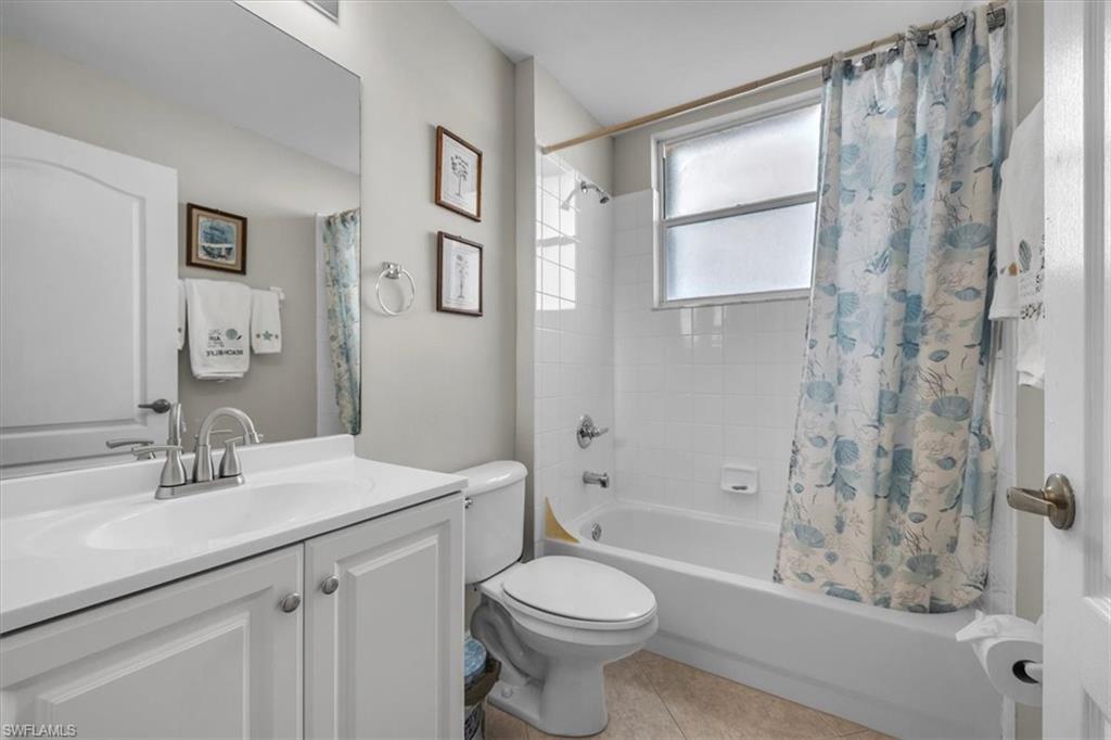 Full bathroom with shower / tub combo with curtain, vanity, and light tile patterned flooring