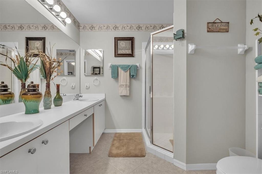 Full bathroom with a shower stall, double vanity, and light tile patterned floors