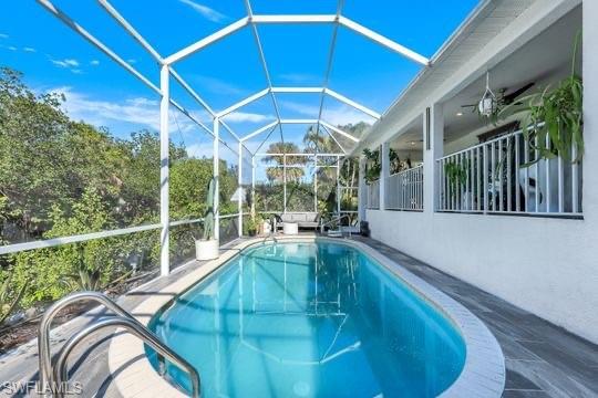 View of swimming pool featuring glass enclosure and ceiling fan