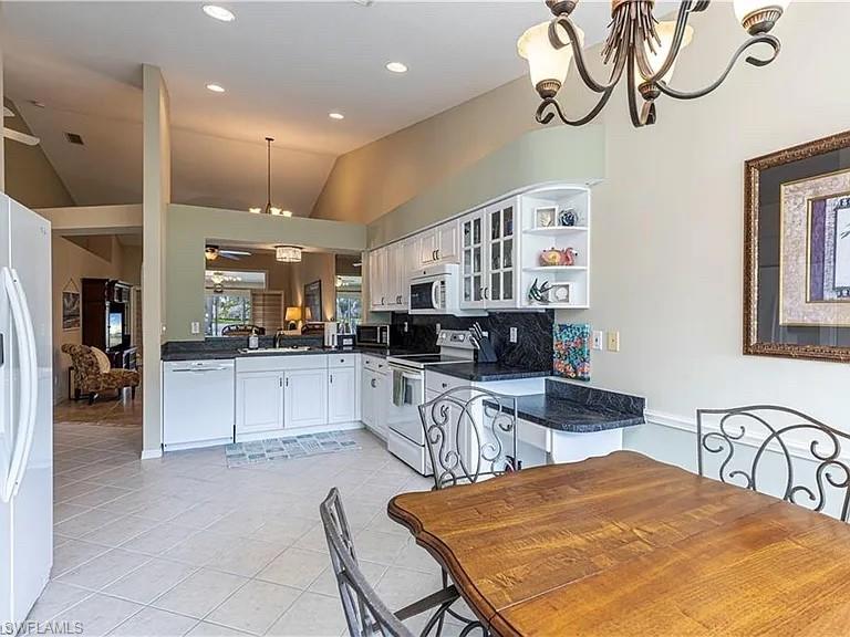 Kitchen with decorative light fixtures, white appliances, open shelves, white cabinets, and a chandelier