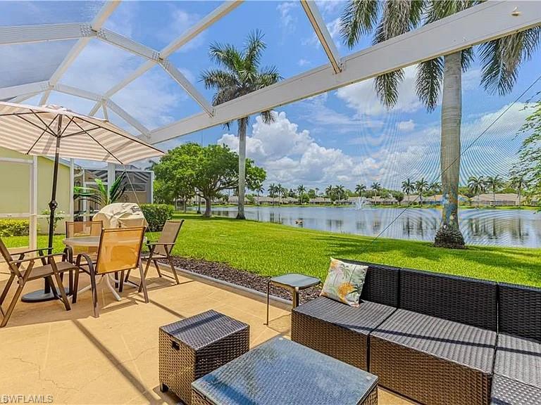 View of patio / terrace featuring a water view, a sunroom, an outdoor living space, and a lanai