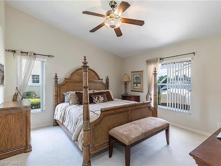 Bedroom with lofted ceiling, light carpet, and a ceiling fan