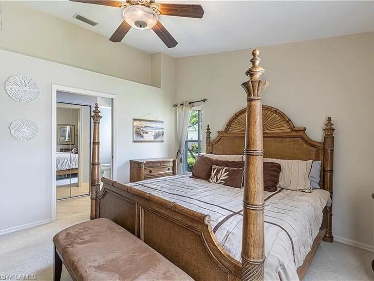 Bedroom featuring light carpet, ensuite bathroom, and a ceiling fan