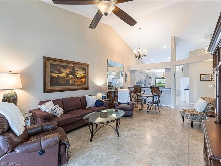 Living room featuring high vaulted ceiling, a chandelier, and ceiling fan