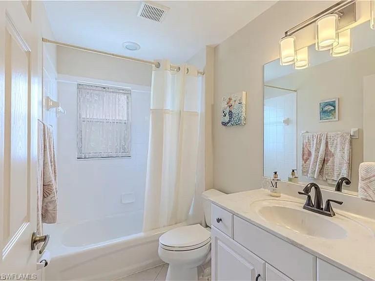 Full bathroom featuring shower / bathtub combination with curtain, vanity, and light tile patterned flooring