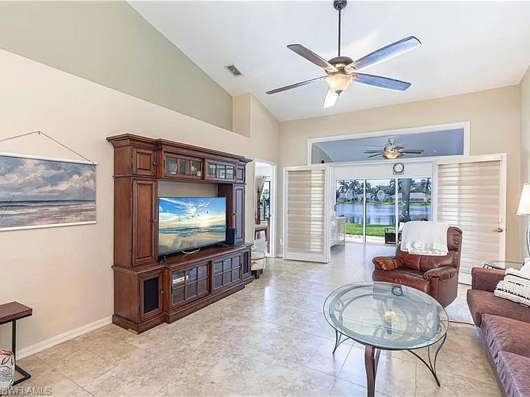 Living room with ceiling fan and high vaulted ceiling