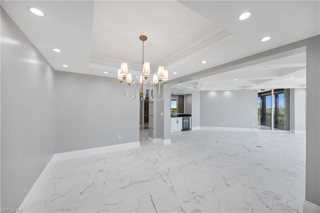 Unfurnished room with a tray ceiling, baseboards, recessed lighting, and a chandelier