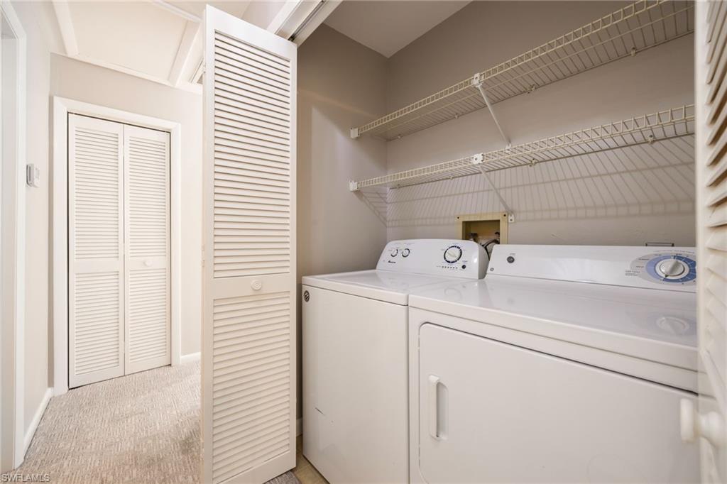Laundry area featuring light colored carpet and washing machine and dryer