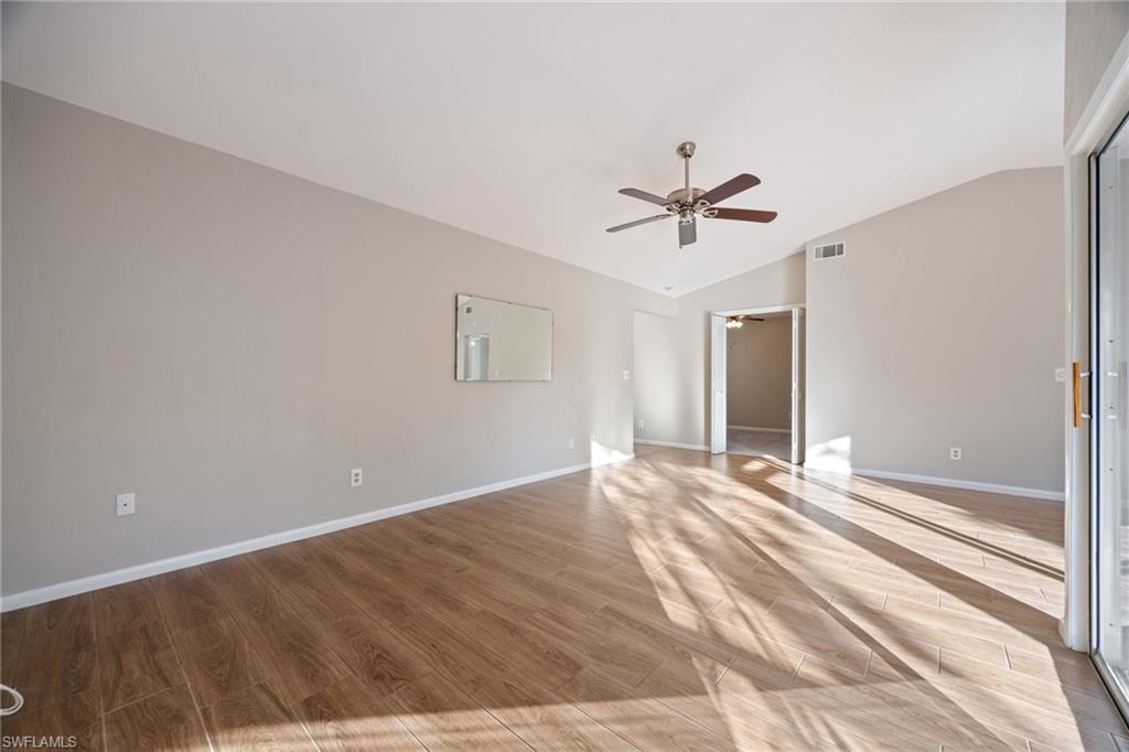 Empty room with vaulted ceiling, light wood-style floors, and a ceiling fan