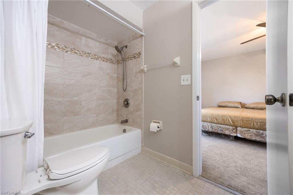 Bathroom with shower / bath combo with shower curtain, light tile patterned floors, light colored carpet, connected bathroom, and a ceiling fan