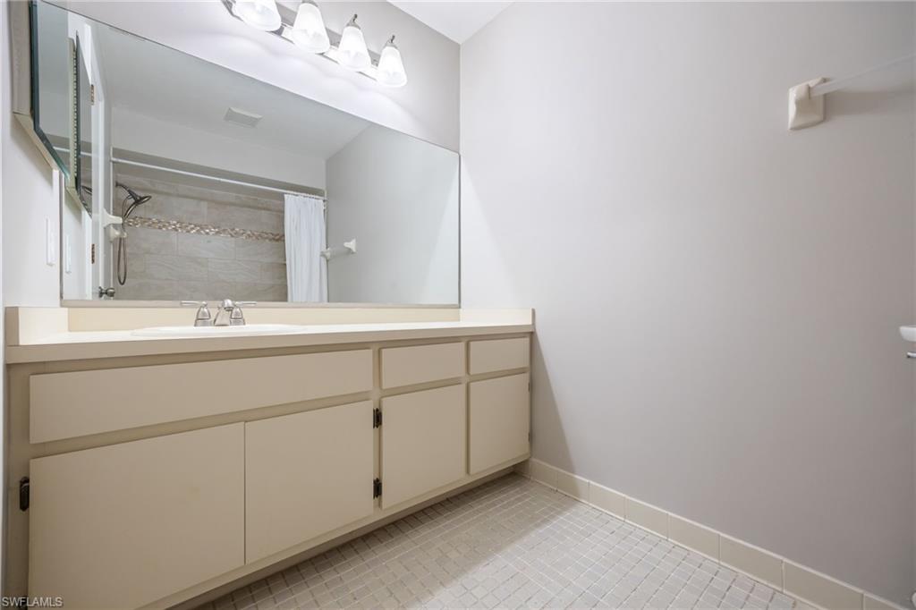 Full bathroom featuring vanity, a tile shower, and light tile patterned floors