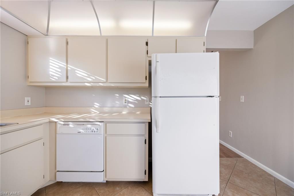 Kitchen with white appliances, light countertops, light tile patterned floors, and white cabinets