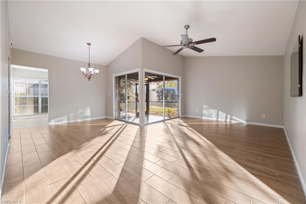 Unfurnished room with wood tiled floors, a ceiling fan, a chandelier, and lofted ceiling