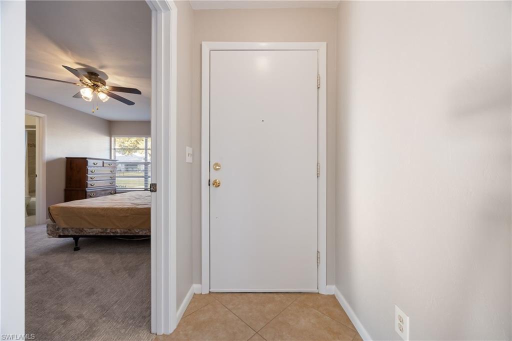 Entryway featuring a ceiling fan, tile patterned flooring, and carpet
