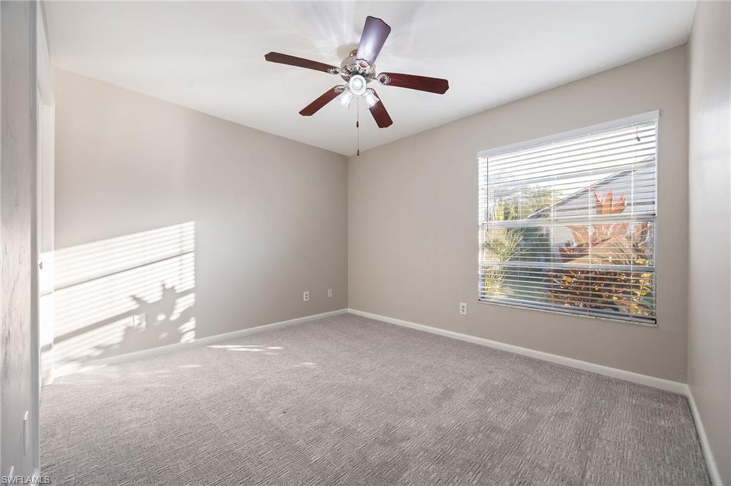 Carpeted spare room with baseboards and ceiling fan