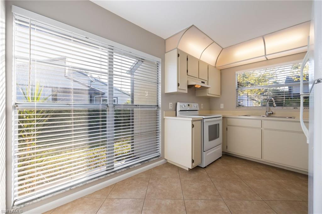 Kitchen with light countertops, white appliances, light tile patterned floors, and healthy amount of natural light