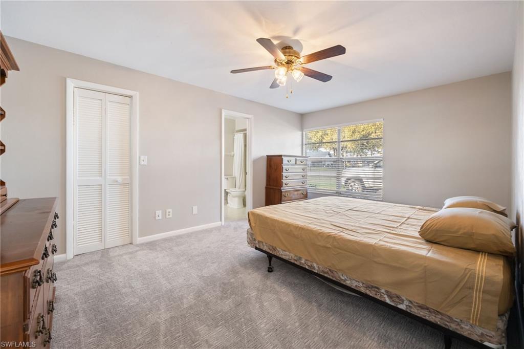 Carpeted bedroom featuring a ceiling fan and ensuite bath