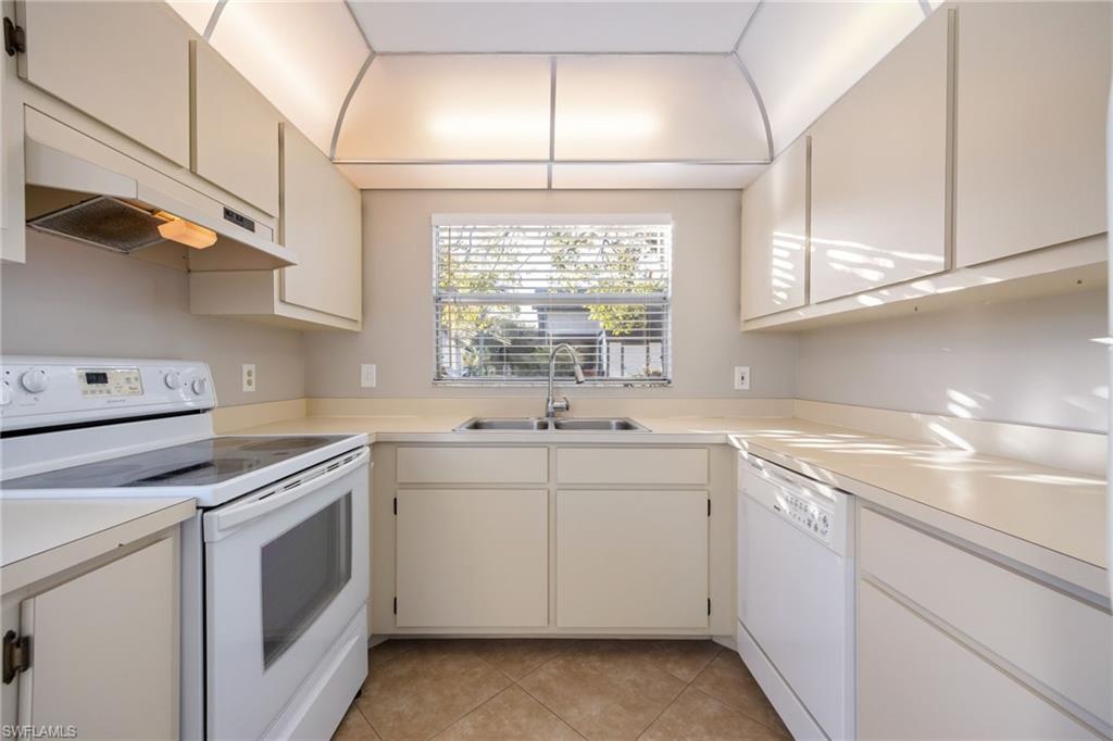Kitchen featuring white appliances, under cabinet range hood, light countertops, and light tile patterned floors